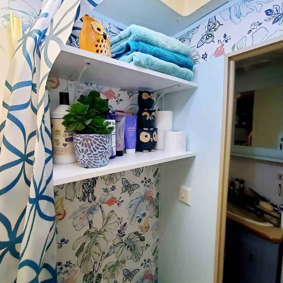 Colorful RV bathroom with white floating shelves storing towels, toiletries, and decorative accents, adding both function and style.