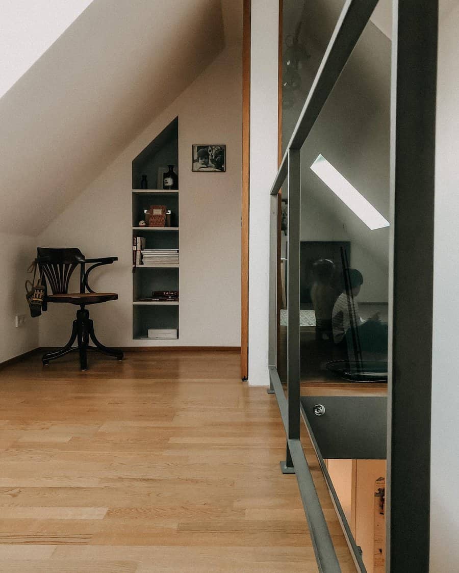 Modern attic space with built-in shelving, a reading nook, wooden flooring, and a sleek glass railing for an open, airy feel.