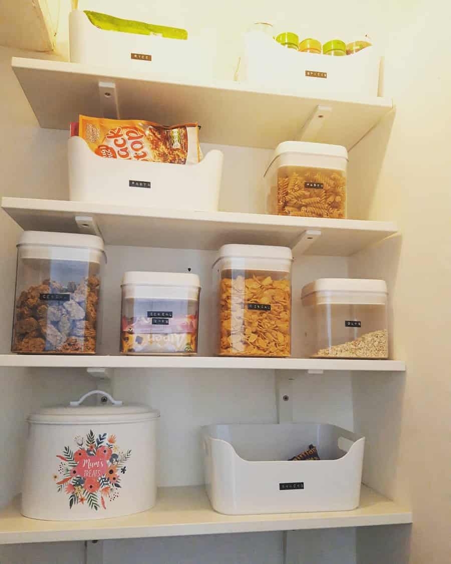 Neatly organized pantry with labeled white bins and airtight containers for cereals, pasta, and snacks on open shelves