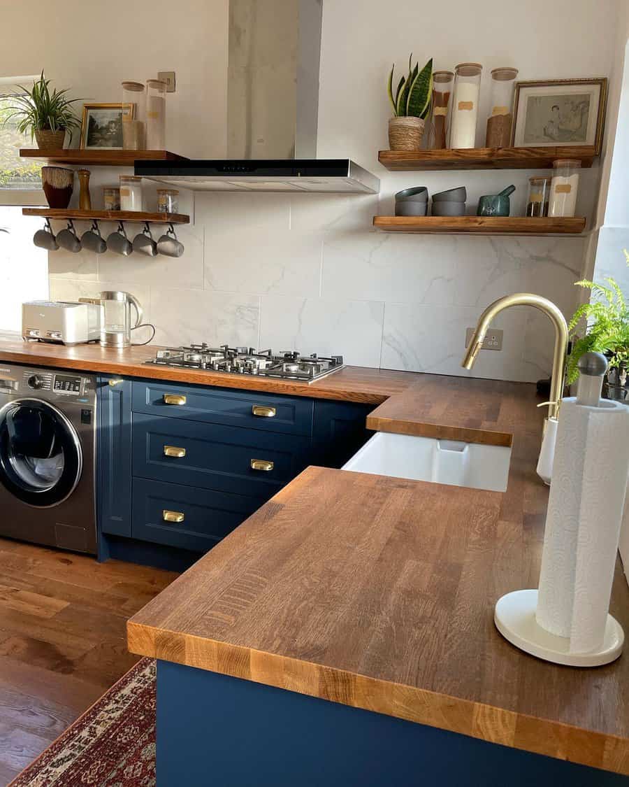 Stylish kitchen with navy cabinets, wooden countertops, open shelves, hanging mugs, and a farmhouse sink for a modern rustic look