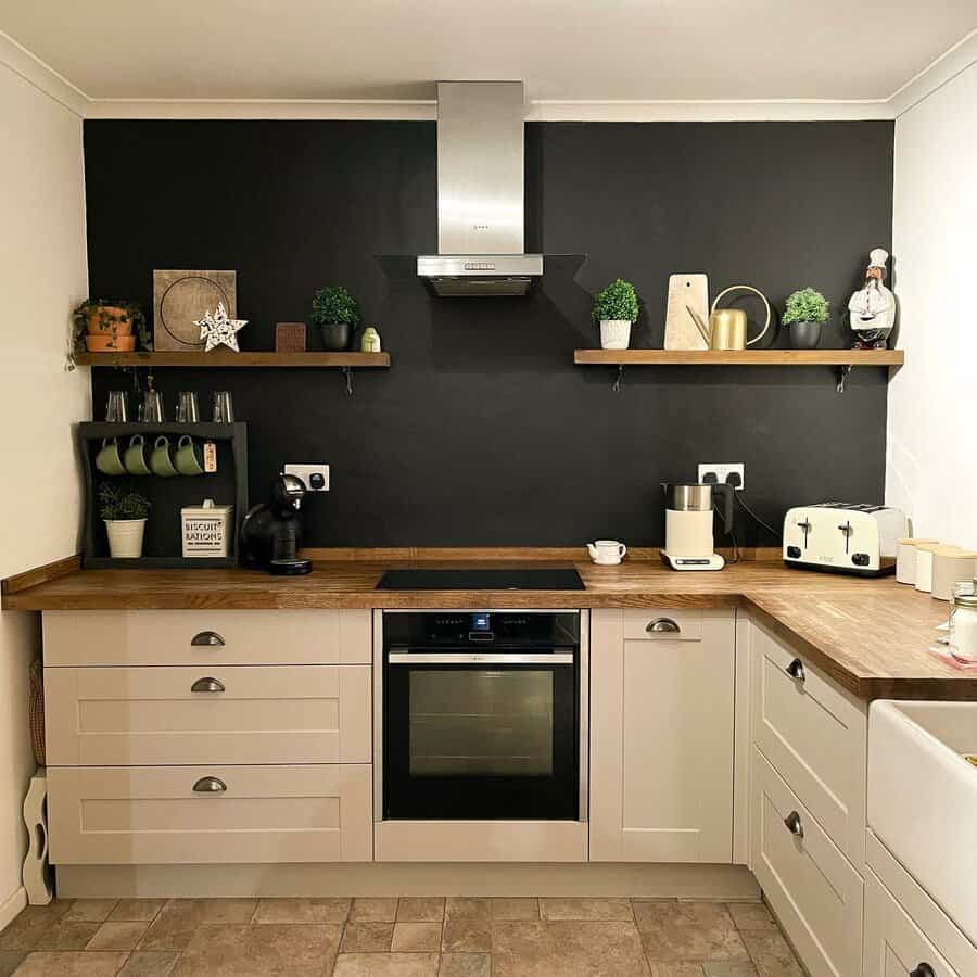 Modern kitchen with black accent wall, open wooden shelves, beige cabinets, and warm lighting for a stylish and cozy atmosphere