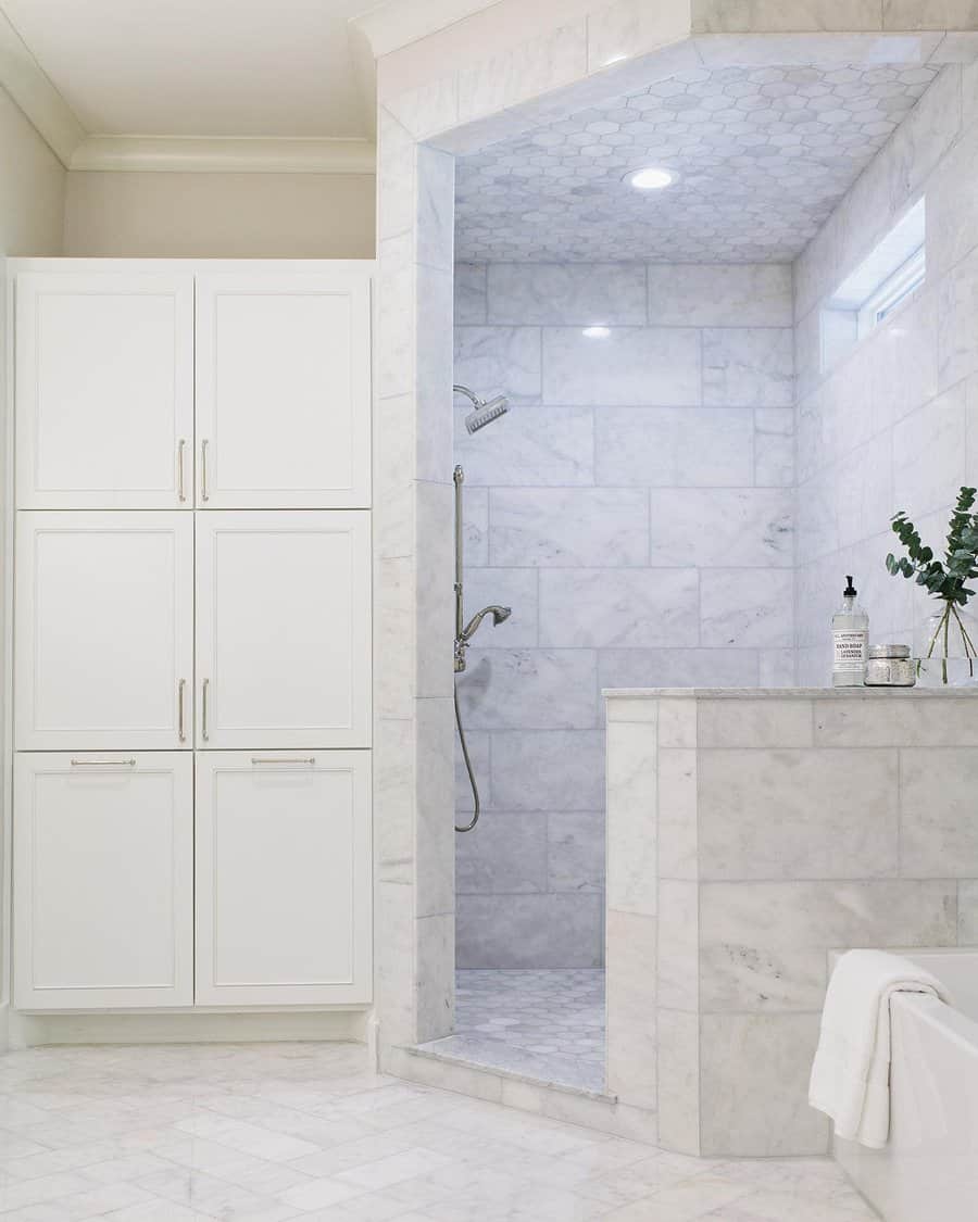 Luxurious bathroom with a marble walk-in shower, hexagonal tile ceiling, and recessed lighting, creating a sleek and spa-like atmosphere.