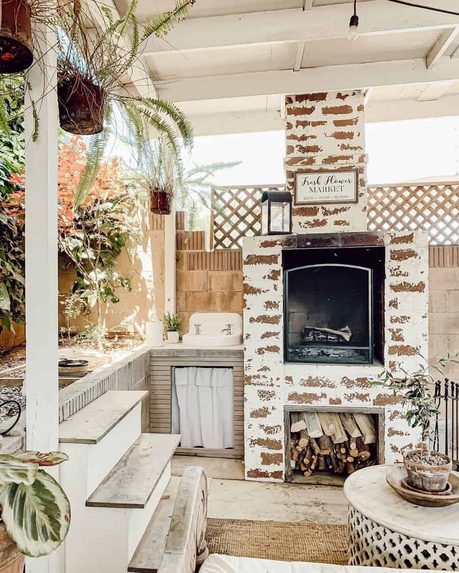 Outdoor rustic patio with a brick fireplace, plants, a wooden bench, and a sign reading "Farm Flowers Market" above the fireplace