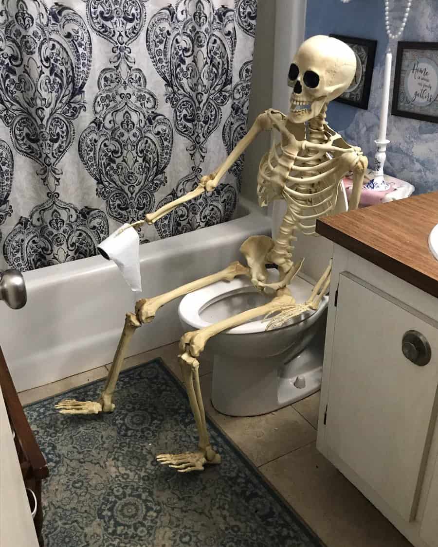 Skeleton seated on a toilet holding toilet paper with a comical expression