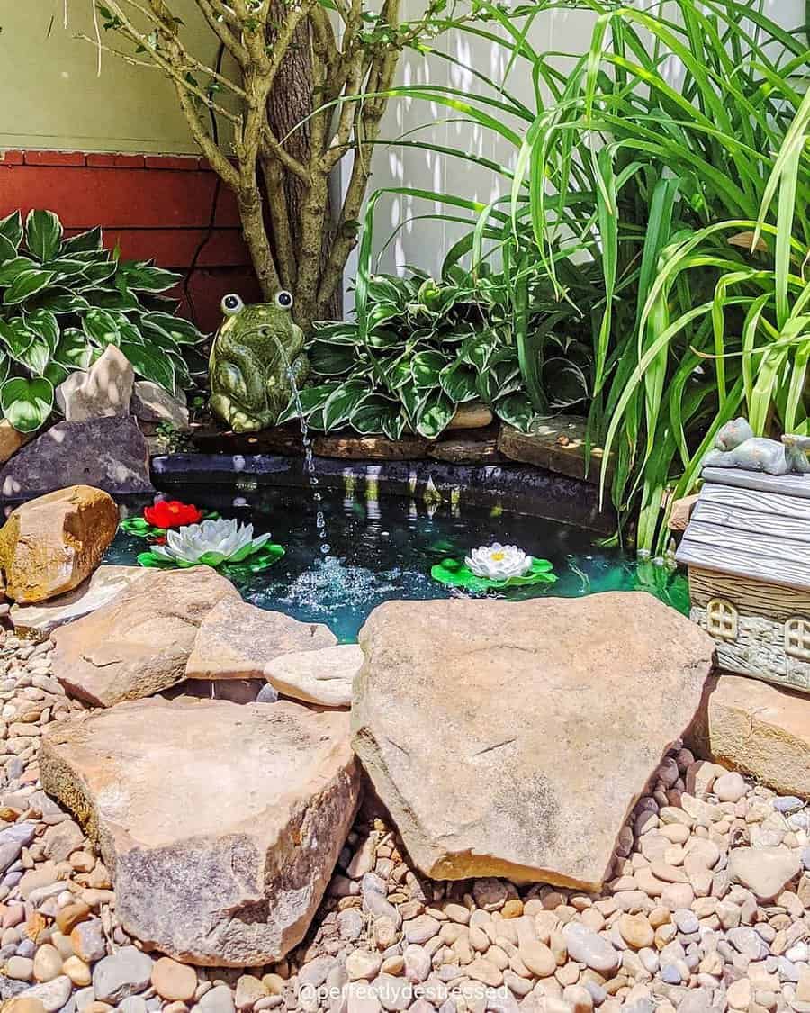 Small garden pond with frog statue and greenery