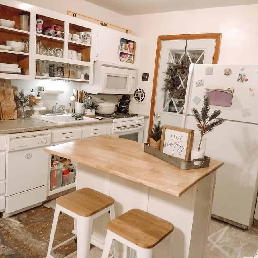 Charming farmhouse-style kitchen with a small wooden breakfast bar, white cabinetry, open shelving, cozy decor, and rustic barstools for a warm touch