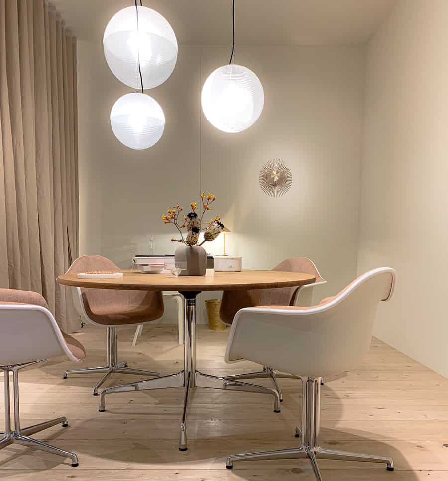 Minimal dining area with round table, modern chairs, and spherical pendant lights; a vase with flowers sits on the table