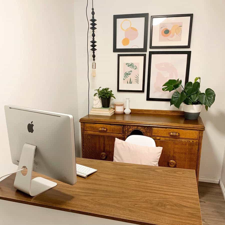 Charming small basement office with a mix of modern and vintage decor, featuring warm wood tones, framed artwork, and lush greenery for a cozy workspace.