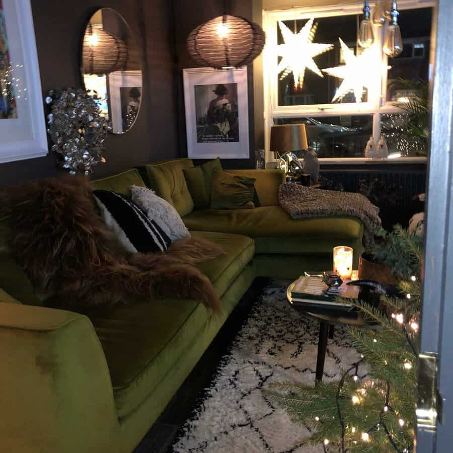 Small living room with a green sofa, soft cushions, star-shaped lights, round mirror, and candles decorated for a relaxing ambiance