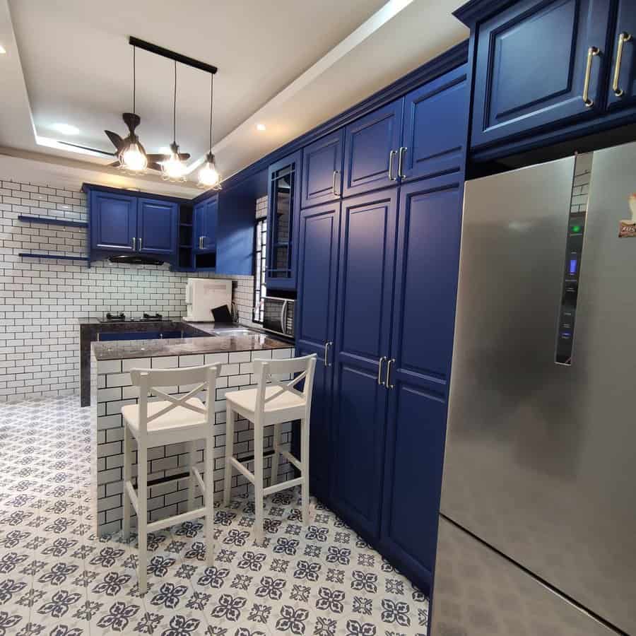 Kitchen with blue cabinets, patterned floor, and white bar stools