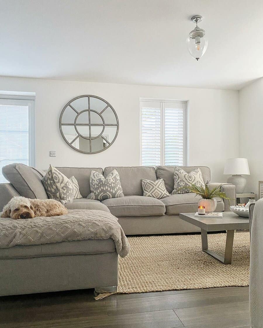 Cozy living room with a sleeping dog on a grey sectional sofa and a round wall mirror