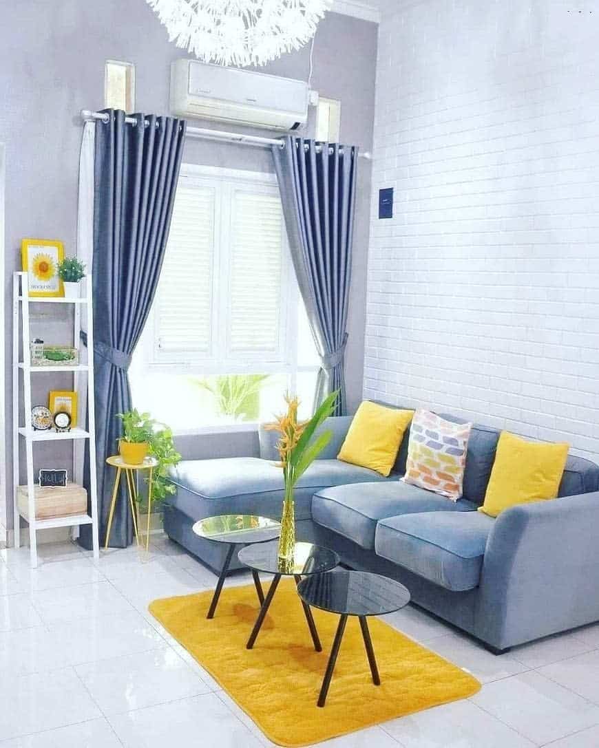 Bright living room with gray sofa, yellow pillows, black coffee tables, yellow rug, and curtains