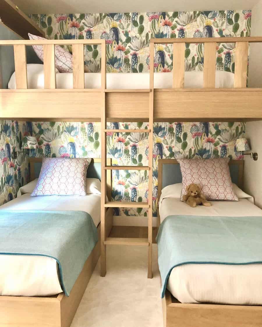 A cozy kids' room with two bunk beds over two single beds, featuring colorful floral wallpaper and a teddy bear on one bed