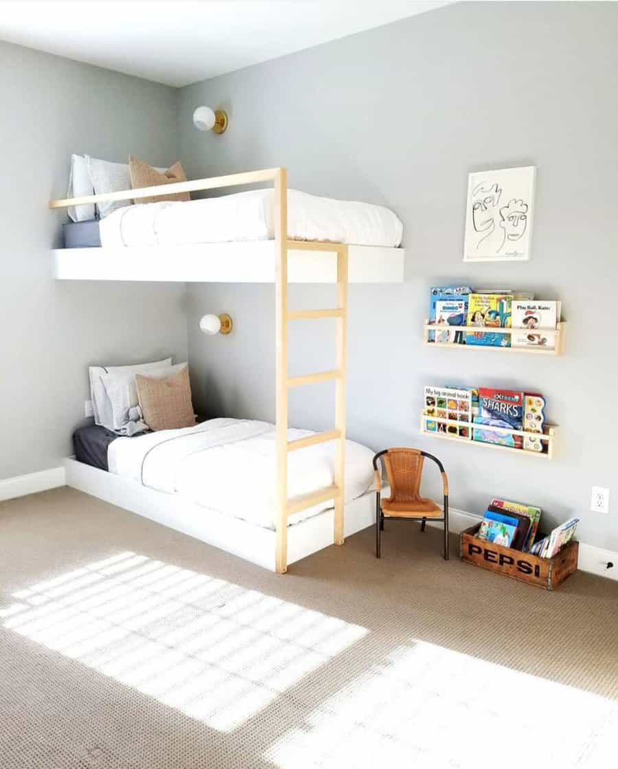 Minimalist kids' room with gray walls, bunk beds, wall shelves with books, and a wicker chair; sunlight casts a patterned shadow