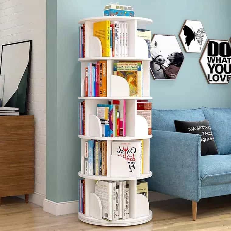 Modern space-saving rotating bookshelf in a stylish living room, filled with colorful books, next to a blue sofa and decorative wall art.