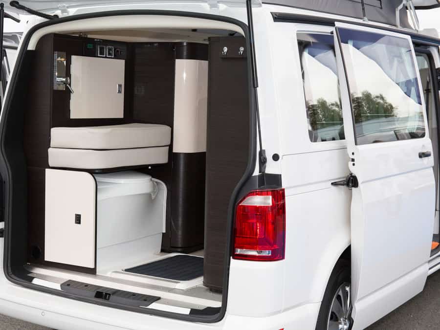 Compact camper van interior with built-in storage, a foldable seat, and a hidden compartment, maximizing space efficiency.