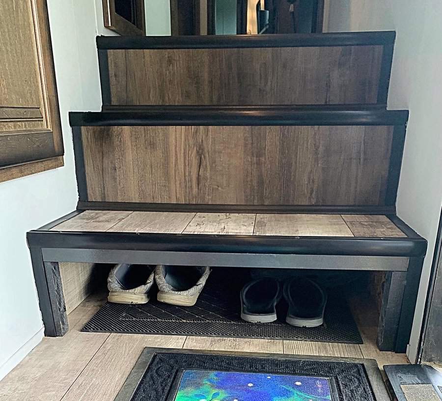 RV entryway with built-in shoe storage under the bottom step, providing a practical and space-saving solution for footwear organization.