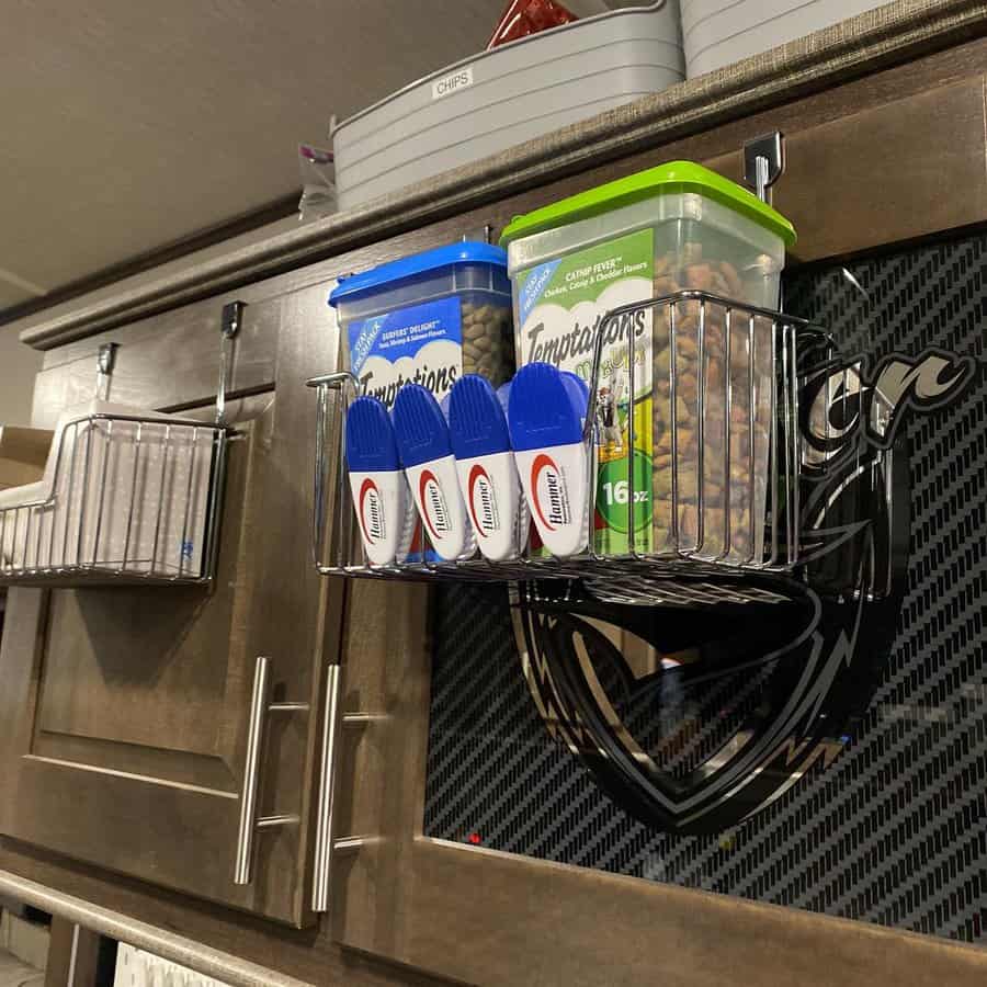 RV kitchen with mounted wire baskets for pet supplies and food storage, maximizing cabinet space with efficient organization.