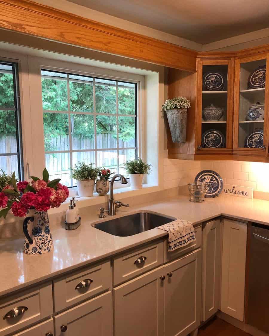 Charming cottage kitchen with a stainless steel sink, warm wood accents, glass-front cabinets, and blue-and-white decor for a classic touch