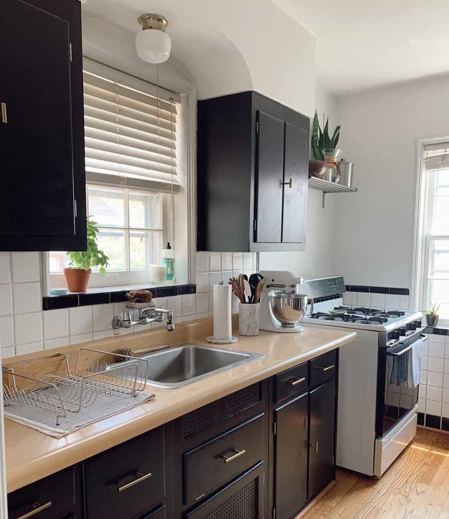 Cozy vintage kitchen with a stainless steel square sink, black cabinets, white tile backsplash, and wooden countertops for a classic contrast