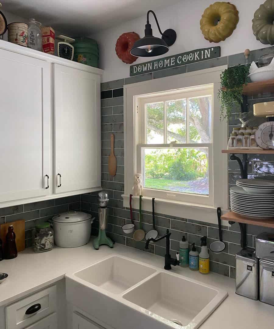 Cozy kitchen with a farmhouse sink, white cabinets, decorative plates, and a "Down Home Cookin'" sign above the window