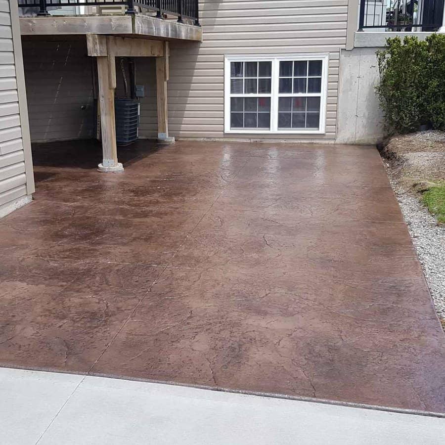 Stained concrete patio next to a house with a deck above