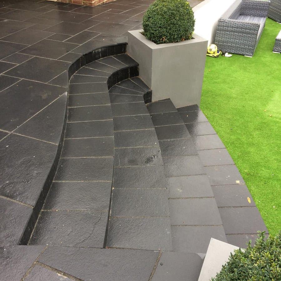 Curved dark slate patio steps with green lawn and planter