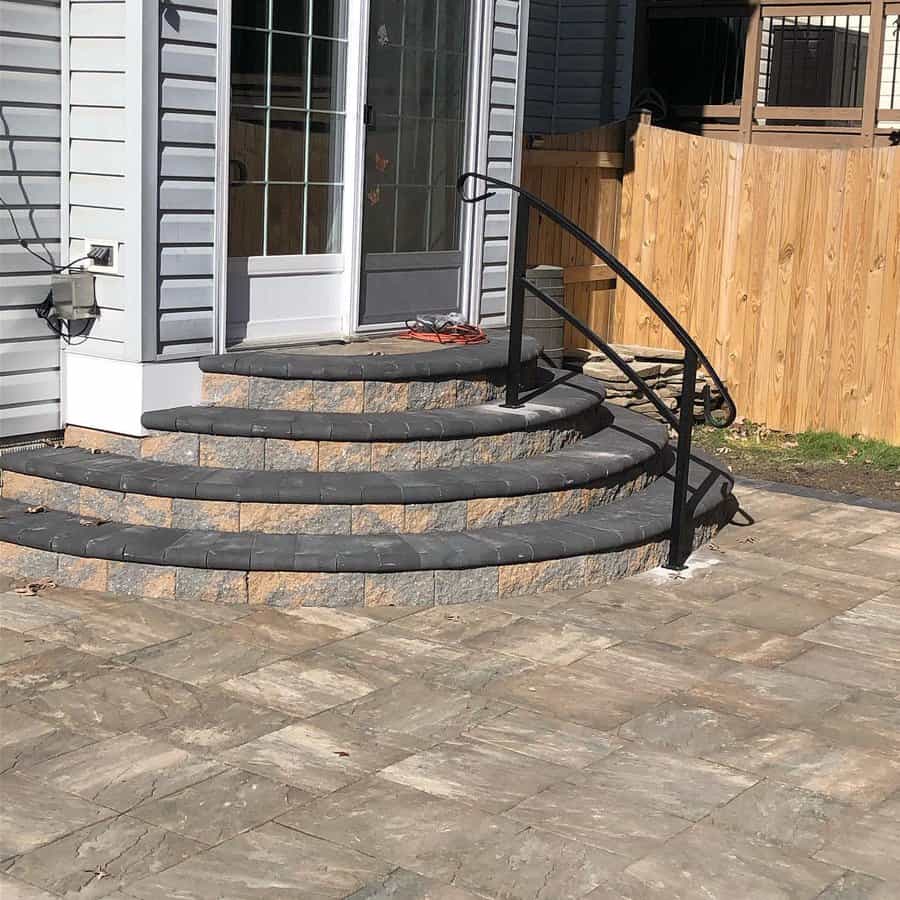 Curved stone patio steps with railing and herringbone pattern