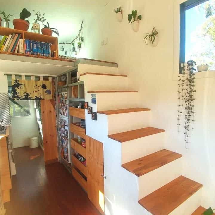 Wooden stairs with storage leading to a loft in a tiny home