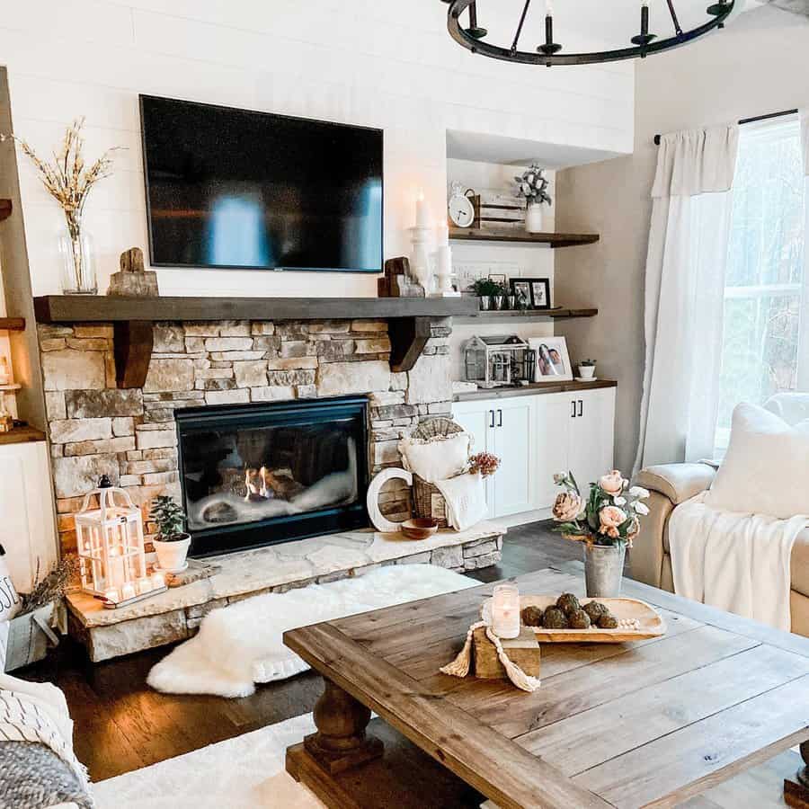 A cozy stone fireplace with a wooden mantel, decorated with candles, plants, and framed photos, creating a warm and inviting living room space