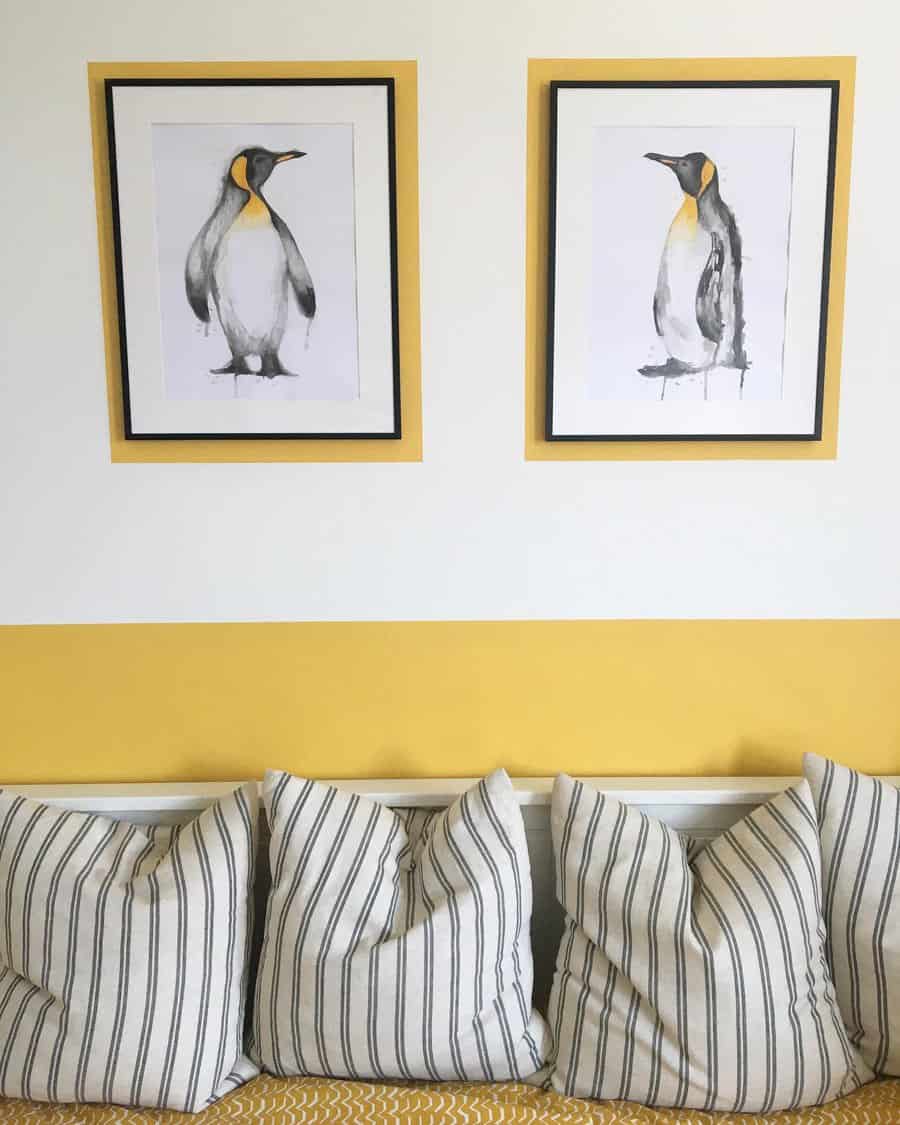 Framed penguin illustrations on a wall above a daybed with striped cushions