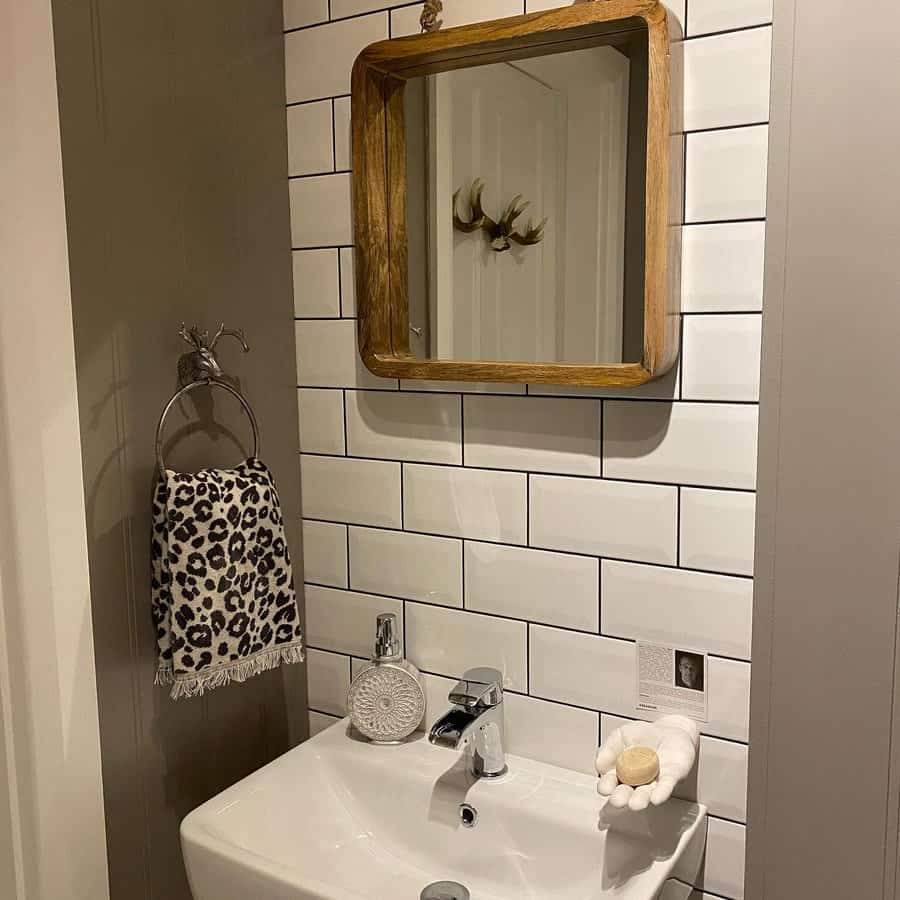 Chic bathroom with white subway tile backsplash, wood-framed mirror, modern sink, and quirky hand-shaped soap holder.