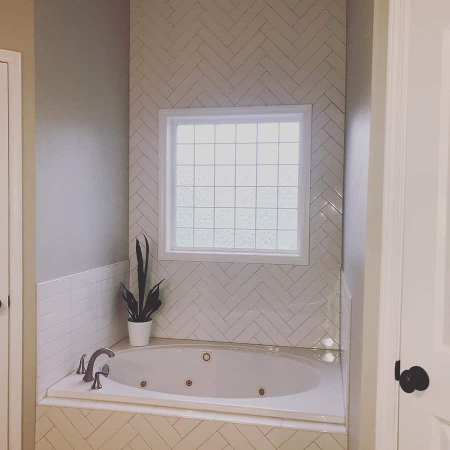 Elegant corner bathtub with herringbone tile and window