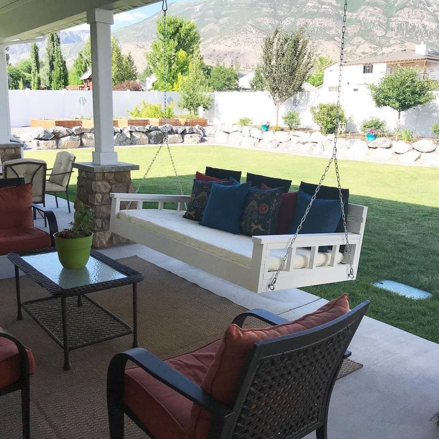 Charming white swing daybed with plush cushions and colorful pillows, creating a cozy and inviting outdoor retreat with mountain views