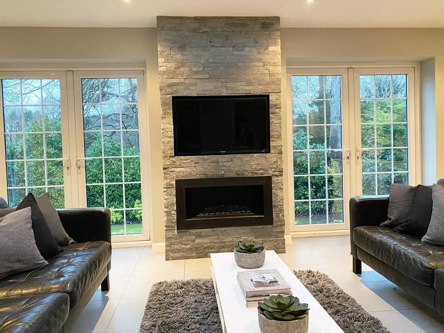 A modern stone fireplace with a sleek black frame, wall-mounted TV above, and minimalist decor, offering a stylish, contemporary living space