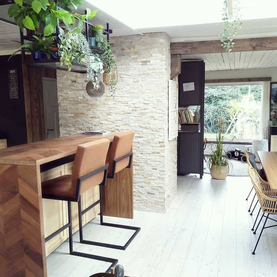 Stylish breakfast bar with a rich wooden table, leather barstools with black metal frames, a stone accent wall, and lush hanging greenery for a cozy vibe