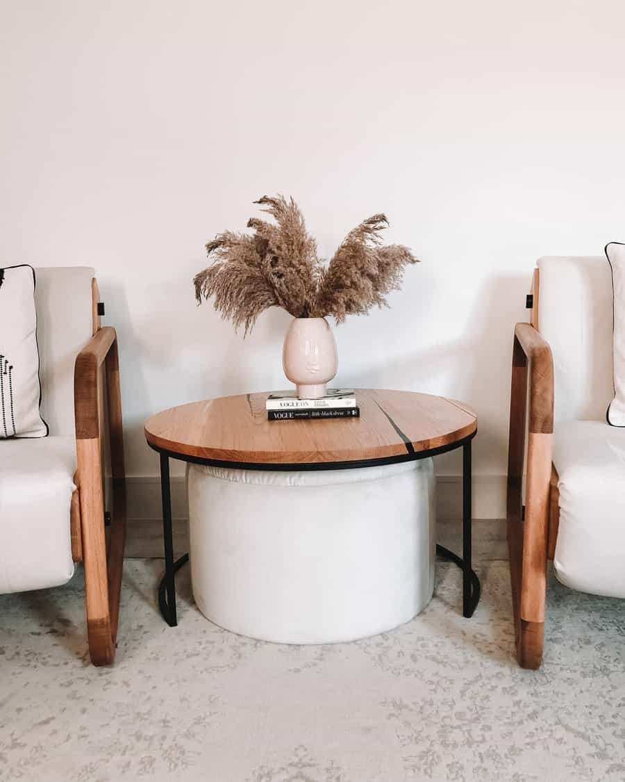 Modern seating area with a round table, vase with pampas grass, and two white chairs