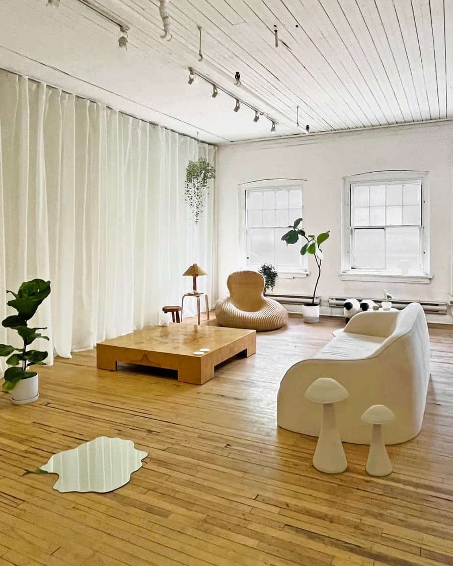 Minimalist living room with white furniture, wooden accents, and large windows