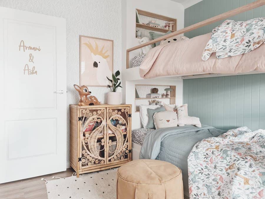 Boho kids' room with bunk beds, blue and floral bedding, a decorative cabinet with toys, wall art, and a plant; light and airy decor