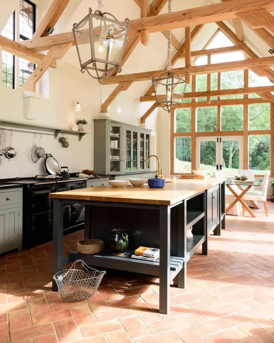 Warm terracotta brick flooring adds rustic charm to this open-concept kitchen, complementing exposed wooden beams and classic cabinetry