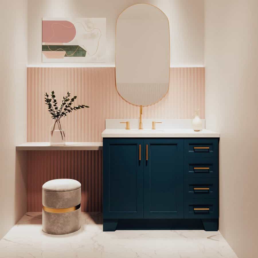 Elegant bathroom with blush pink textured backsplash, oval mirror, navy vanity with gold hardware, and minimalist modern decor.