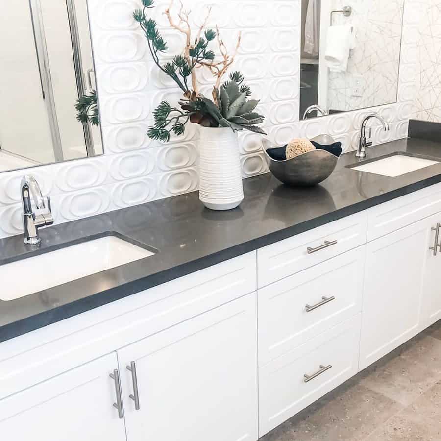 Bright bathroom with modern 3D white textured backsplash, dark countertop, double sinks, and minimalist decor for a clean, stylish look.