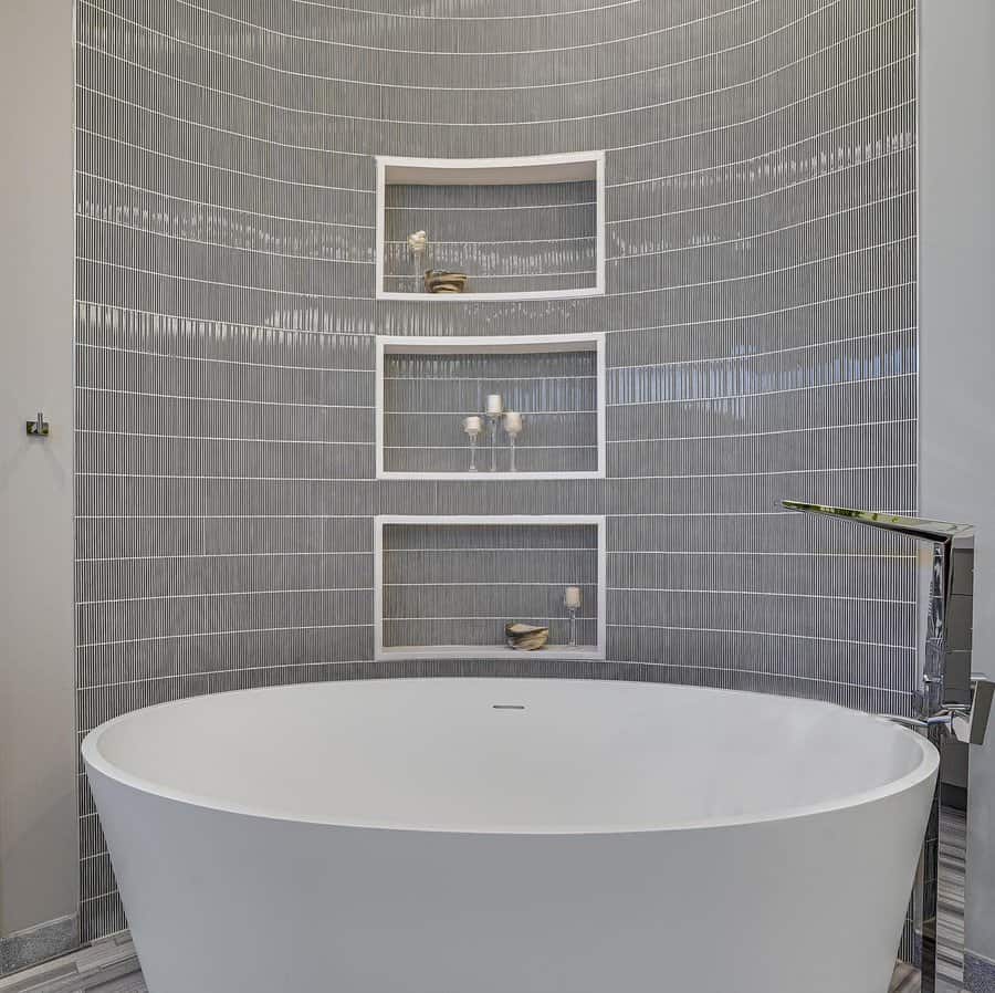 Curved tub with textured wall and niche shelves