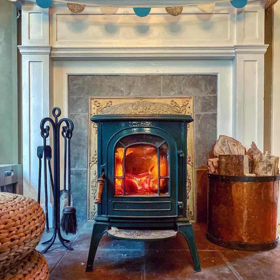 Charming vintage wood stove set in a white mantel fireplace with decorative tile accents, cozy fire tools, and rustic wood storage for a warm ambiance.