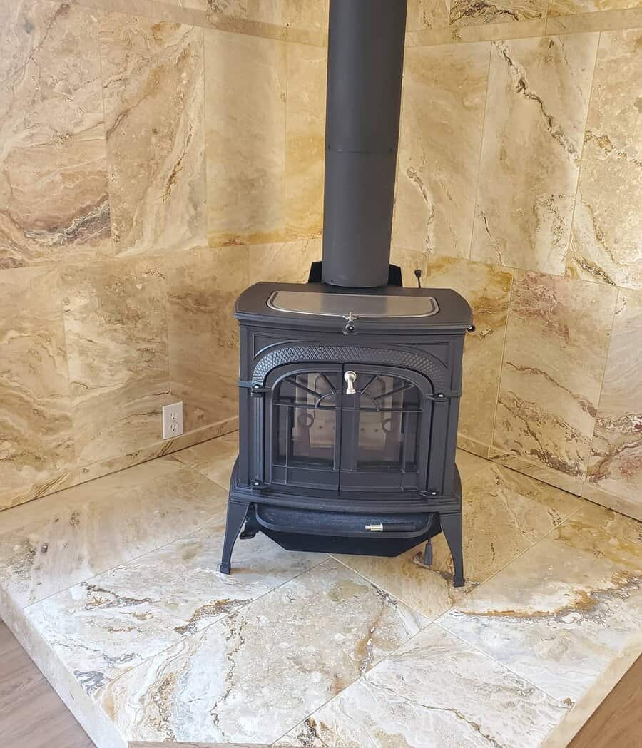 Elegant black wood stove set on a polished marble-tiled hearth, creating a sophisticated and heat-resistant focal point in the corner of the room.