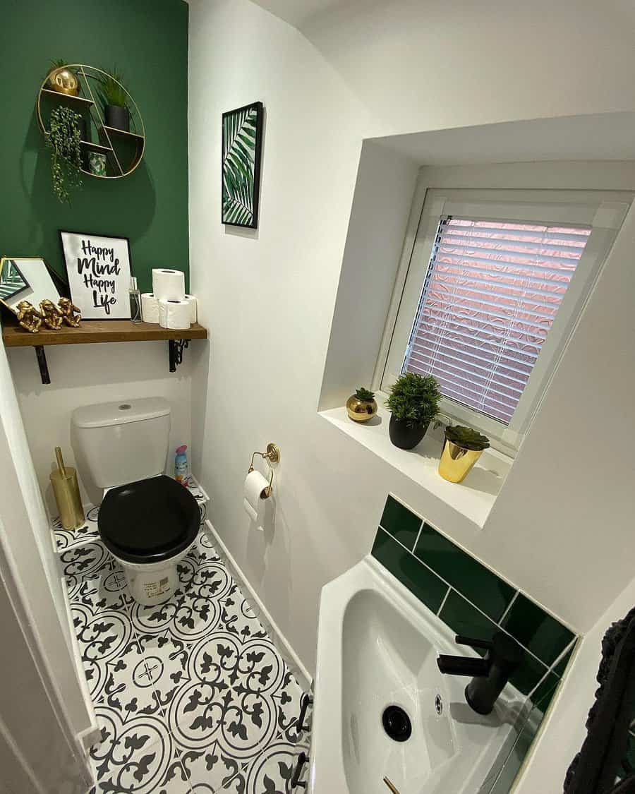 Bold and stylish bathroom with green subway tile backsplash, patterned black-and-white floor tiles, black fixtures, and tropical-themed decor.