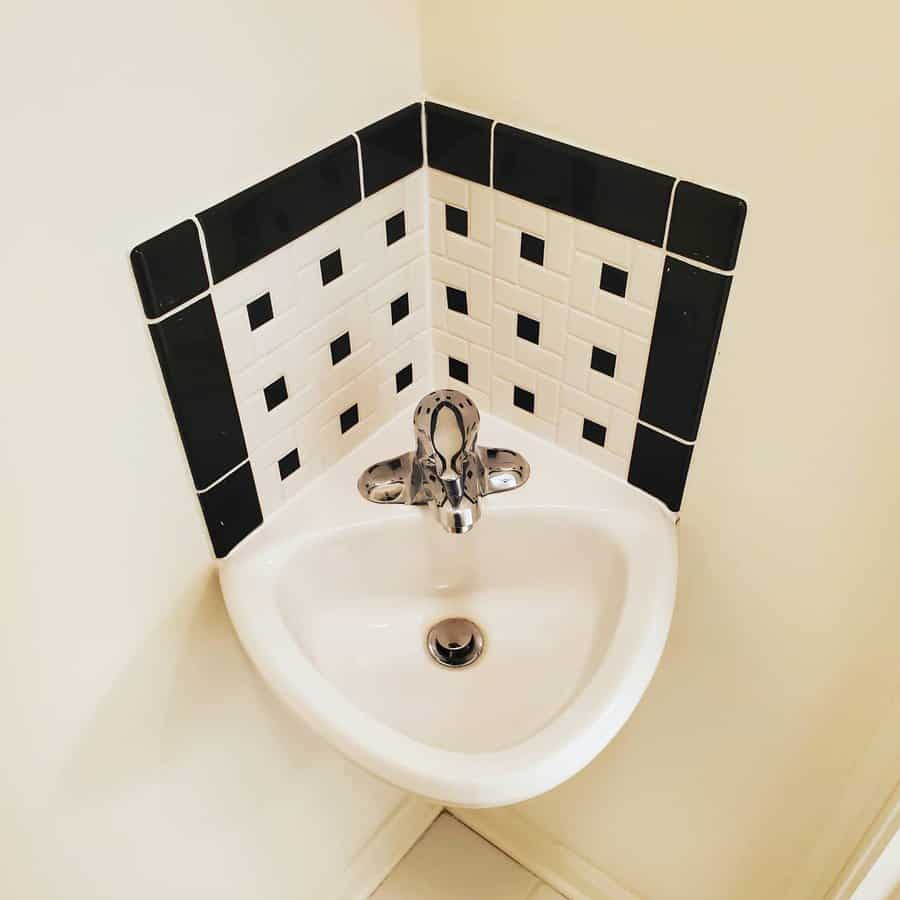 Compact corner sink with a classic black and white tiled backsplash in a checkered pattern, adding a retro touch to a small space.