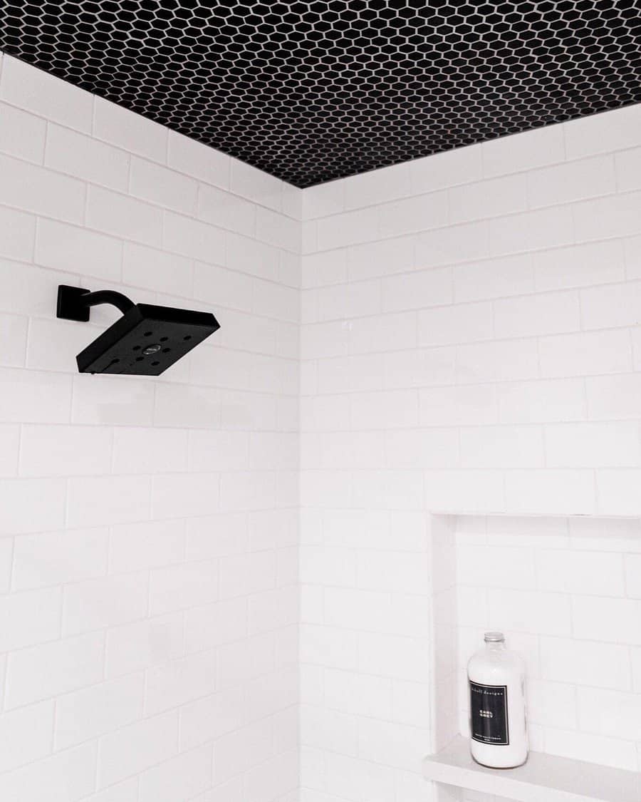 Modern shower with a bold black hexagonal tile ceiling, white subway tile walls, and matte black fixtures, creating a sleek monochrome contrast.