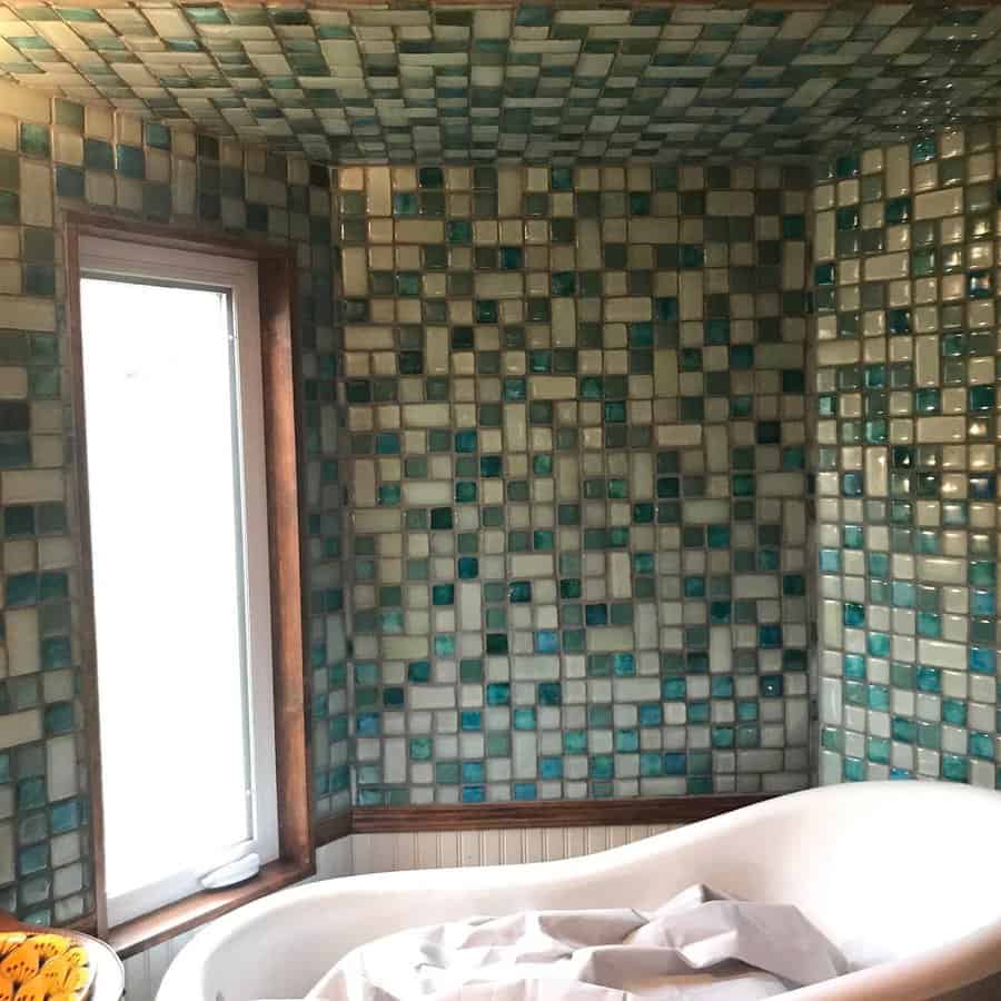 Unique bathroom with handcrafted blue-green mosaic tiles covering the walls and ceiling, creating an immersive, artistic, and spa-like atmosphere.