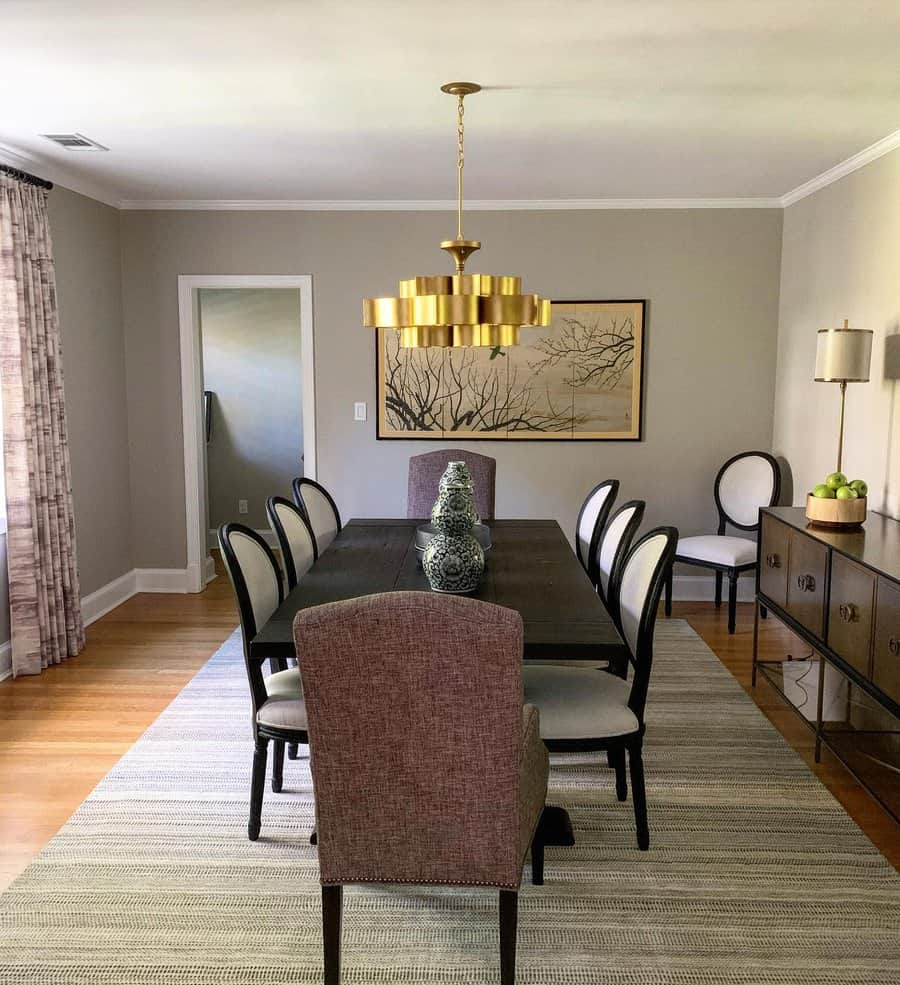 Elegant dining room with a dark table, eight chairs, gold chandelier, and framed artwork; neutral walls and large window